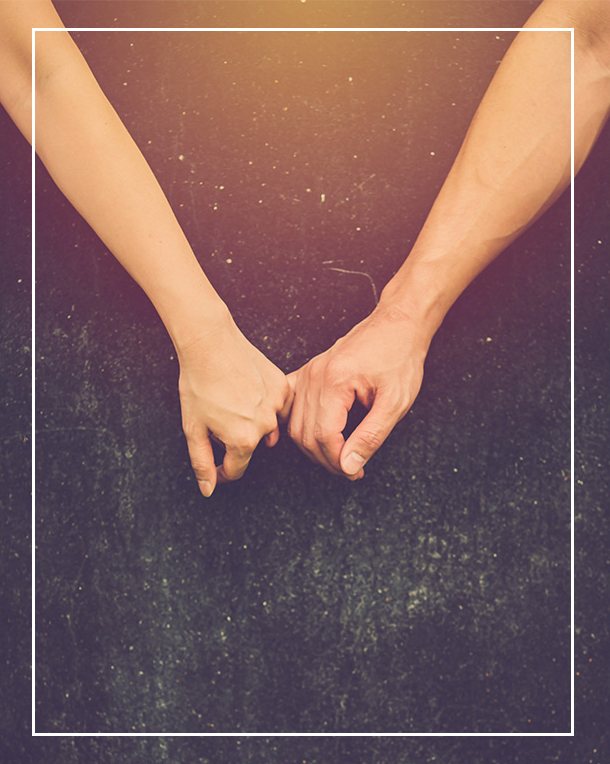 Photo showing the arms of a man and woman holding pinky fingers.